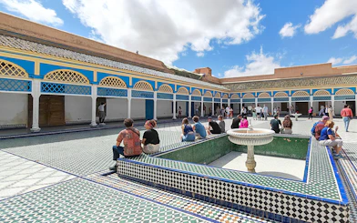 Bahia Palace courtyard with visitors seated around a fountain, Marrakech.