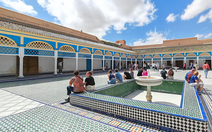 Bahia Palace courtyard with visitors seated around a fountain, Marrakech.