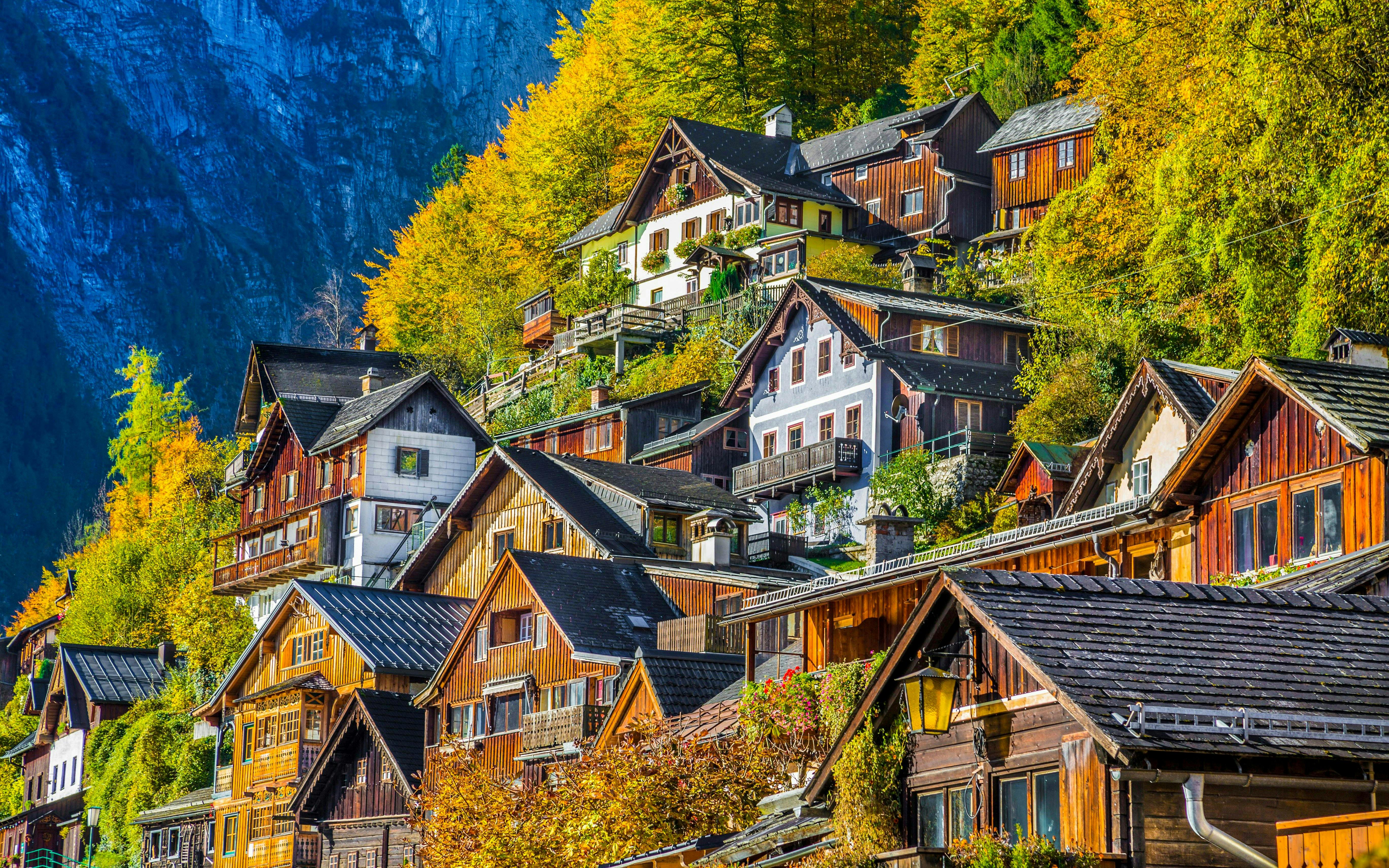 Wooden houses on a hillside in Hallstatt's old town, Austria, surrounded by autumn foliage.