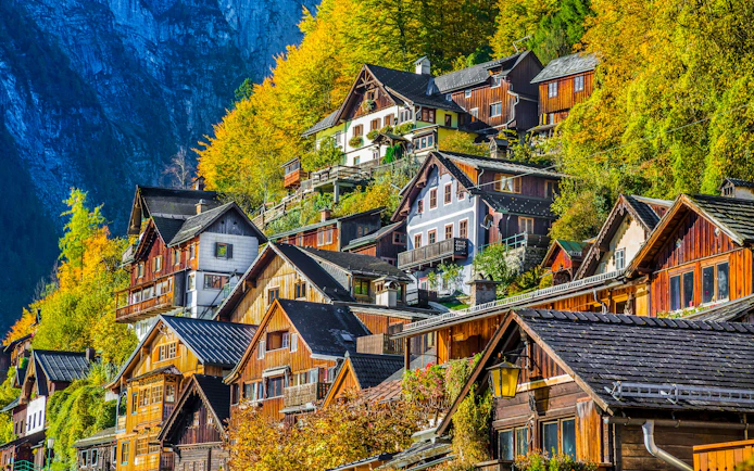 Wooden houses on a hillside in Hallstatt's old town, Austria, surrounded by autumn foliage.