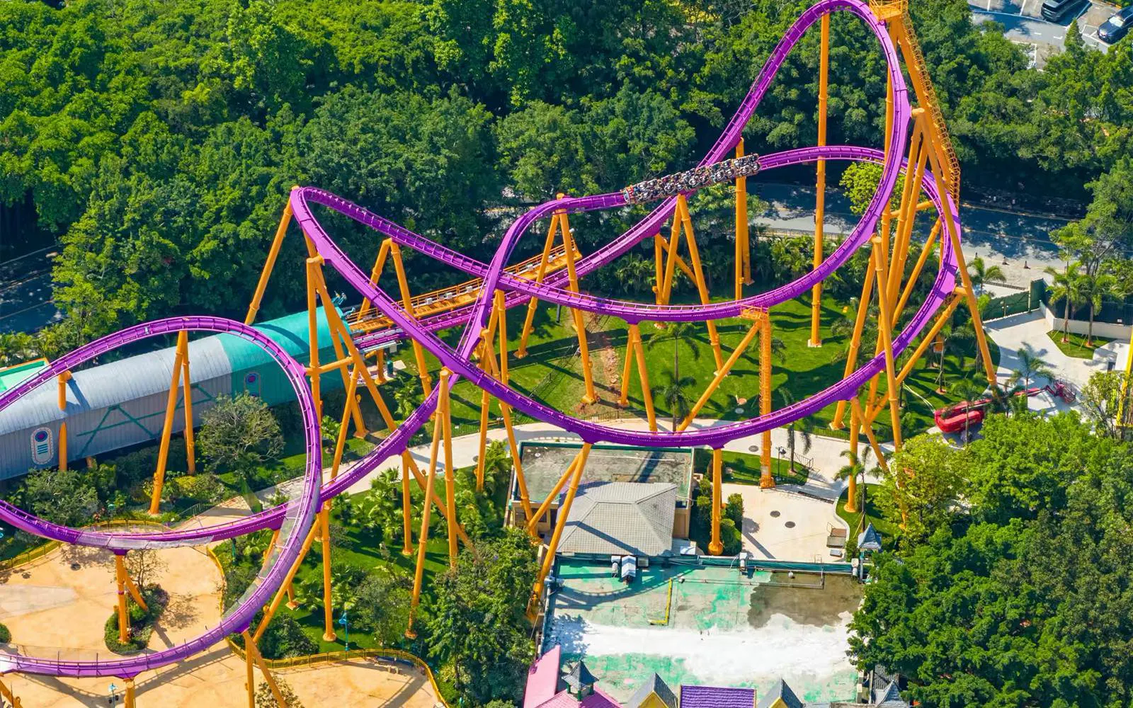 Roller coaster at Chimelong Paradise, Guangzhou, with vibrant purple tracks and lush greenery.