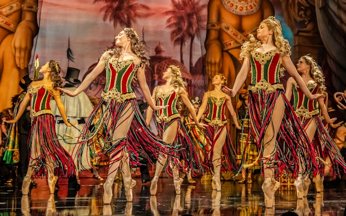 Dancers in colorful costumes perform on stage during Phantom of the Opera production.