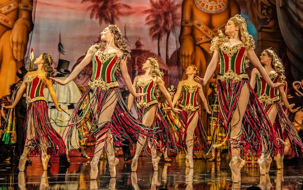 Dancers in colorful costumes perform on stage during Phantom of the Opera production.