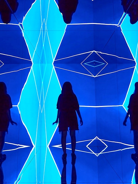 Guest exploring geometric light installation at Light Art Museum.