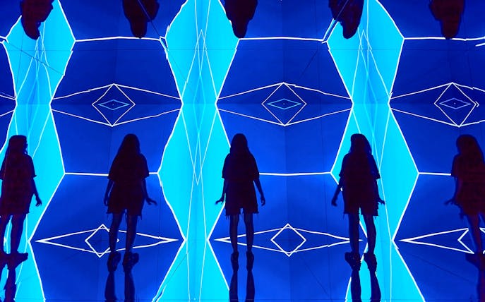 Guest exploring geometric light installation at Light Art Museum.