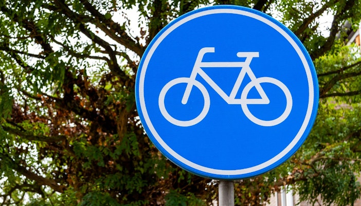 Bicycle route sign on a tree-lined path.