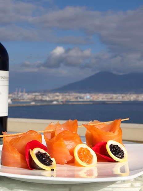 Romantic rooftop dinner with wine and seafood overlooking Naples and Mount Vesuvius.