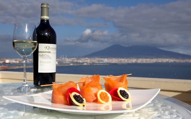 Romantic rooftop dinner with wine and seafood overlooking Naples and Mount Vesuvius.