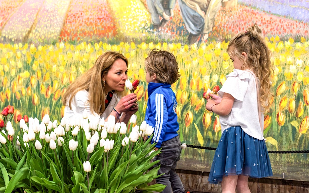 Family picking tulips in an indoor garden with colorful mural backdrop.