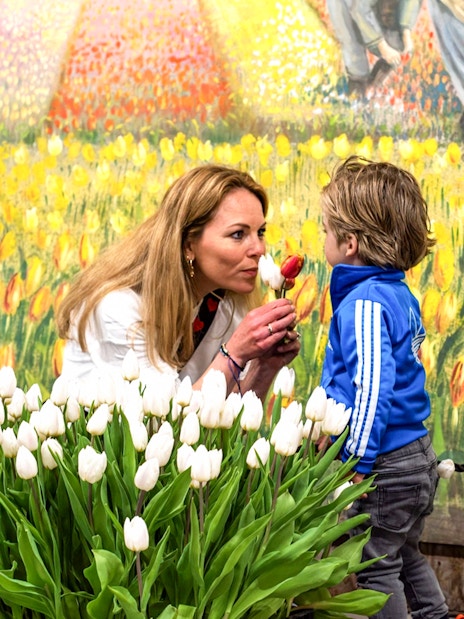 Family picking tulips in an indoor garden with colorful mural backdrop.