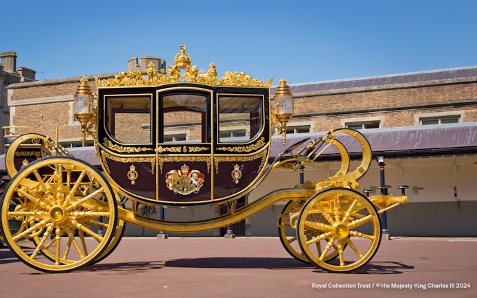 Diamond Jubilee State Coach with ornate gold detailing in front of a historic building.