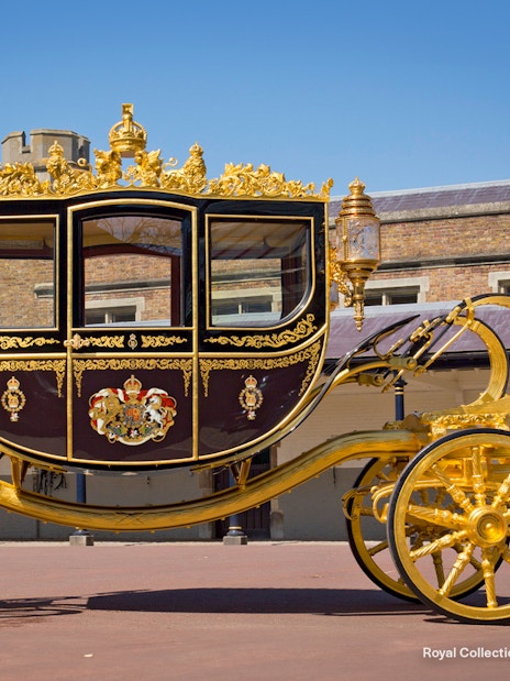 Diamond Jubilee State Coach with ornate gold detailing in front of a historic building.