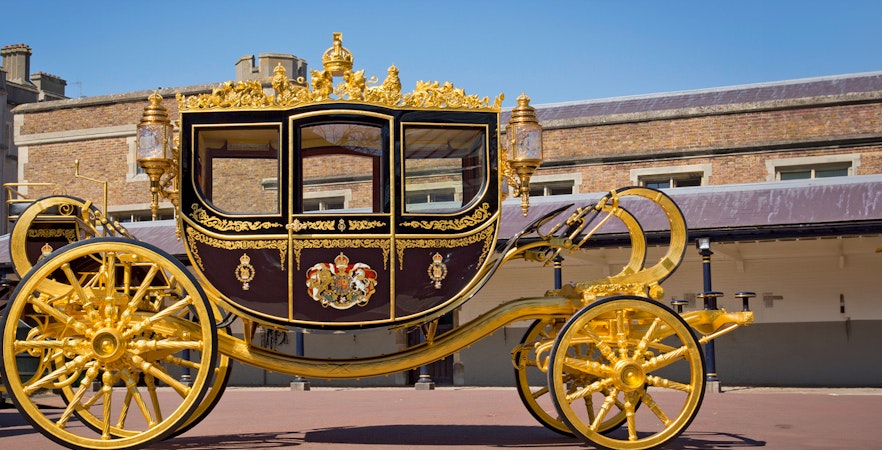 Diamond Jubilee State Coach with ornate gold detailing in front of a historic building.