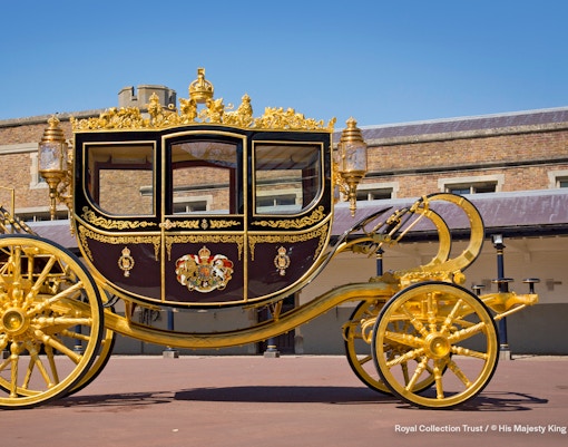 Diamond Jubilee State Coach with ornate gold detailing in front of a historic building.
