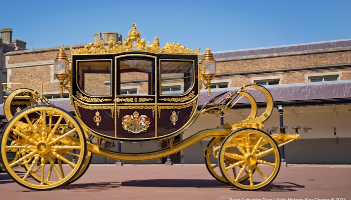 Diamond Jubilee State Coach with ornate gold detailing in front of a historic building.