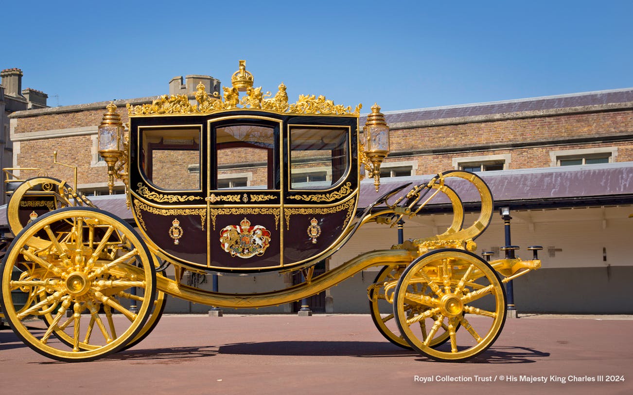 Diamond Jubilee State Coach with ornate gold detailing in front of a historic building.
