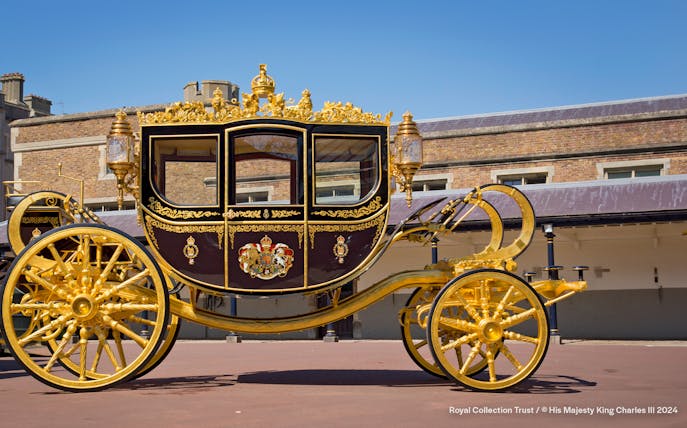 Diamond Jubilee State Coach with ornate gold detailing in front of a historic building.
