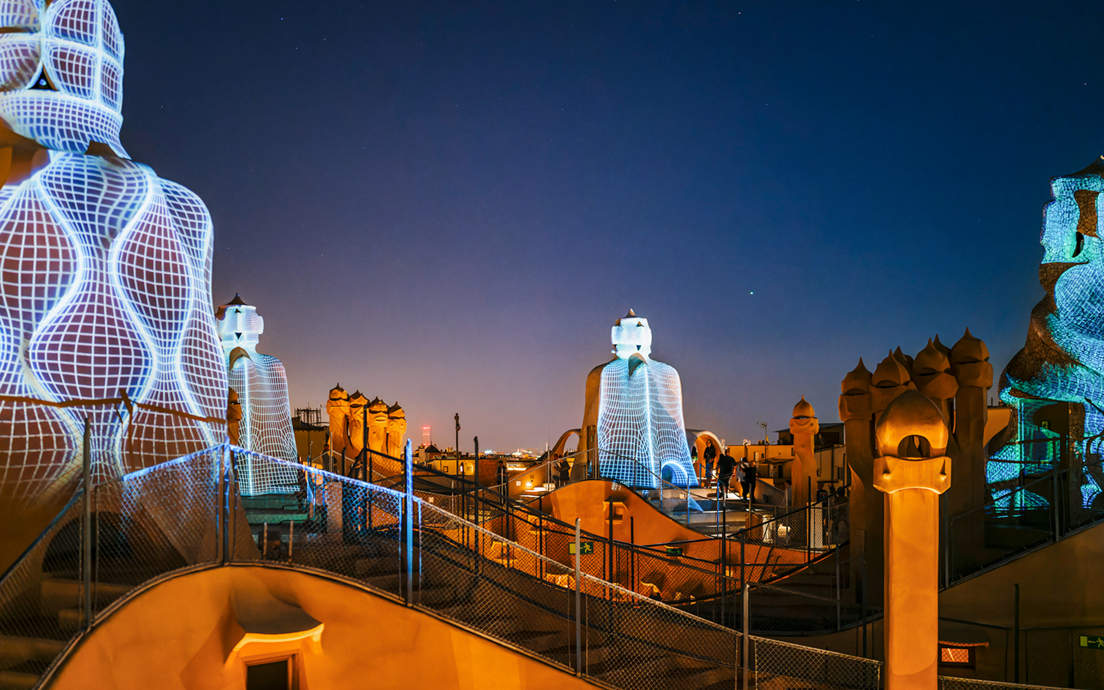 Casa Mila rooftop at night with illuminated chimneys during La Pedrera Night Experience in Barcelona.