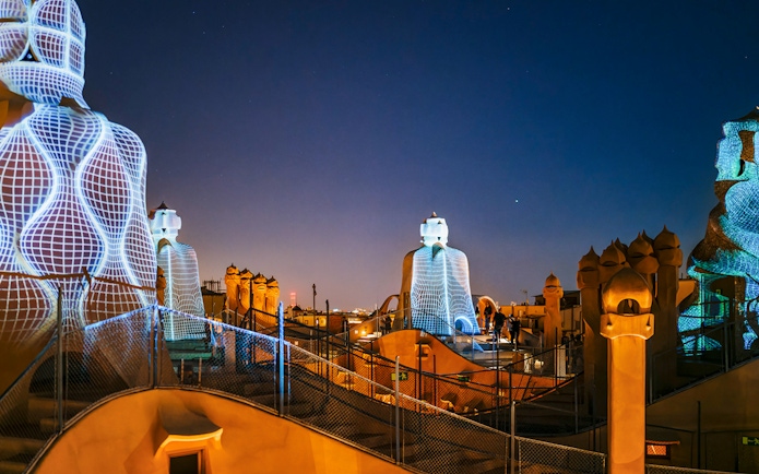 Casa Mila rooftop at night with illuminated chimneys during La Pedrera Night Experience in Barcelona.