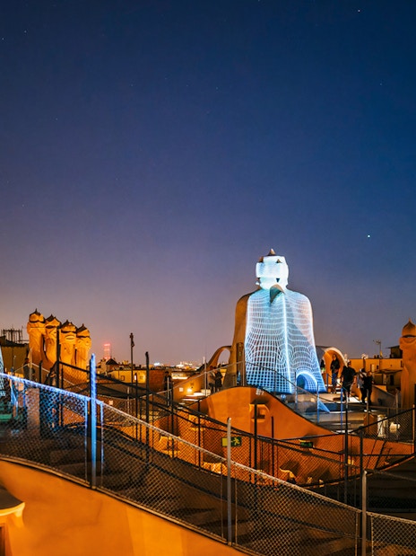 Casa Mila rooftop at night with illuminated chimneys during La Pedrera Night Experience in Barcelona.