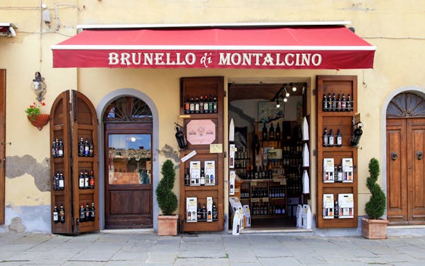 Wine shop entrance in Montalcino, Italy, featuring Brunello bottles on display.