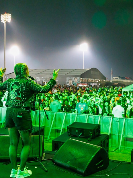 Performer on stage at Emirates Dubai 7s with a cheering crowd at night.