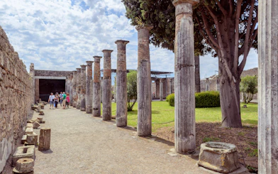 Visitors exploring ancient columns at Pompeii ruins, Italy.