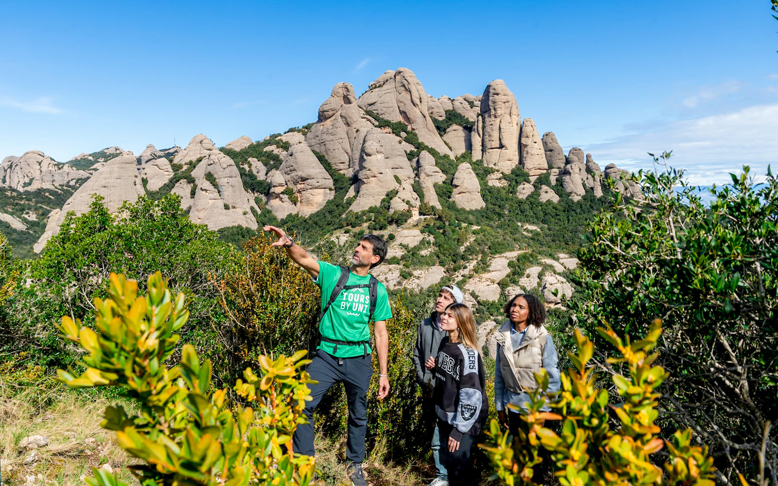 Tourists with guide on Montserrat mountain hike observing local plants.
