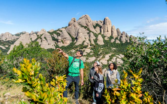 Tourists with guide on Montserrat mountain hike observing local plants.