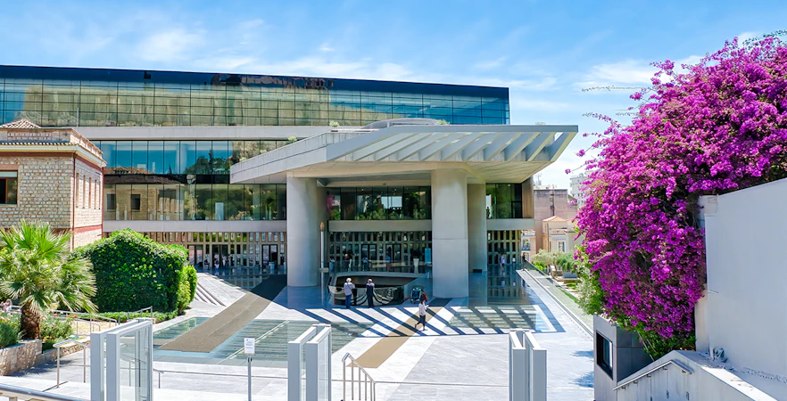 Acropolis Museum entrance with modern architecture and vibrant flowers, Athens, Greece.