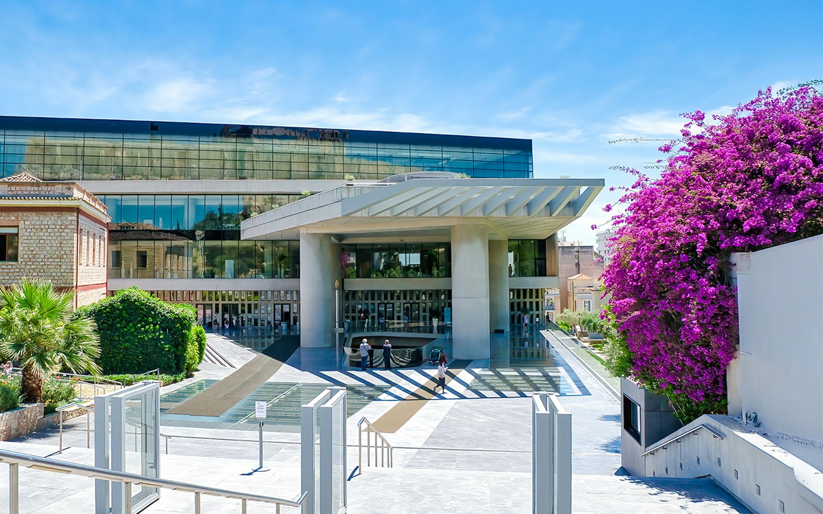 Acropolis Museum entrance with modern architecture and vibrant flowers, Athens, Greece.