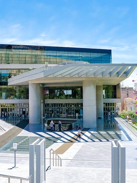 Acropolis Museum entrance with modern architecture and vibrant flowers, Athens, Greece.