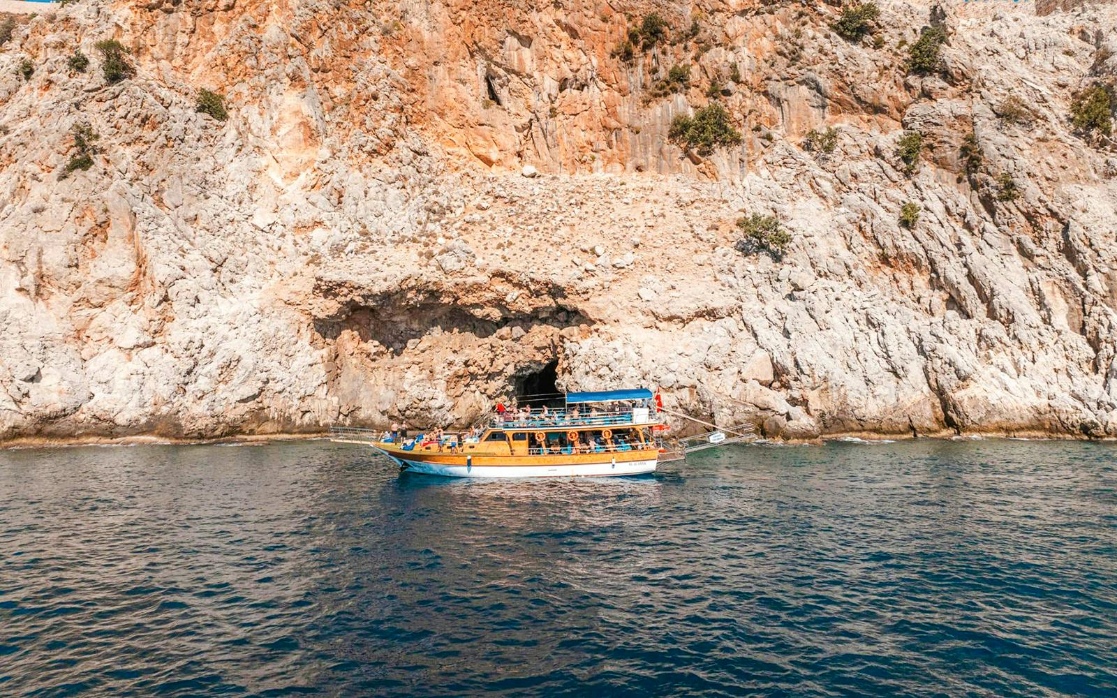 Boat cruising near rocky cliffs during Alanya Boat Day Tour.