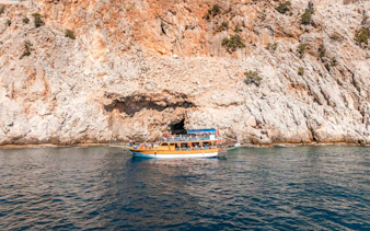 Boat cruising near rocky cliffs during Alanya Boat Day Tour.