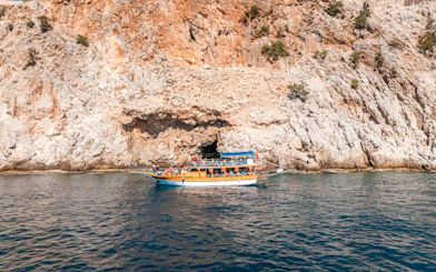 Boat cruising near rocky cliffs during Alanya Boat Day Tour.