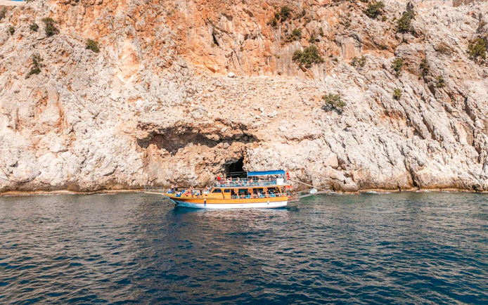 Boat cruising near rocky cliffs during Alanya Boat Day Tour.