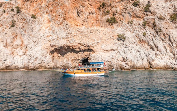 Boat cruising near rocky cliffs during Alanya Boat Day Tour.