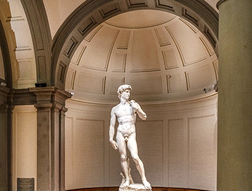 Statue of David in Florence's Accademia Gallery with visitors gathered around.