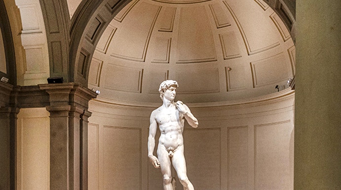Statue of David in Florence's Accademia Gallery with visitors gathered around.
