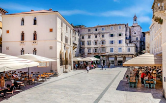 Old town square with cafes and historic buildings in Split, Croatia, near Diocletian's Palace.