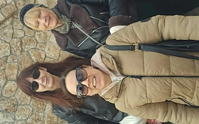Three people smiling in front of a stone wall in Benalmádena Pueblo during a self-guided city exploration game.