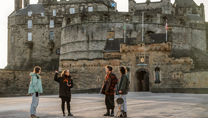 Tour guide revealing secrets of the Royal Mile with a view of Edinburgh Castle in the background, Edinburgh, Scotland