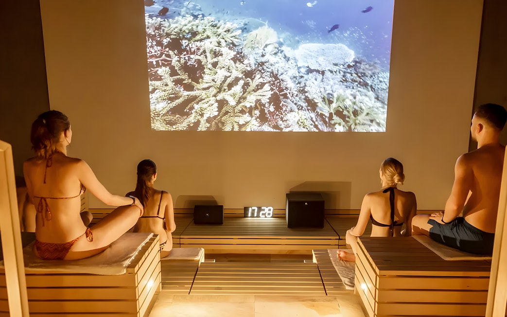 Visitors relaxing in a sauna at Therme Bucuresti Spa, watching an underwater video.