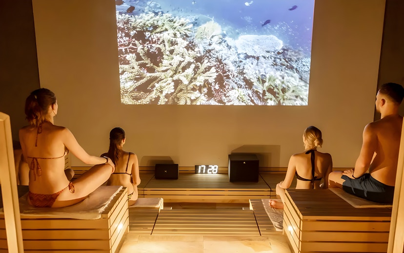 Visitors relaxing in a sauna at Therme Bucuresti Spa, watching an underwater video.