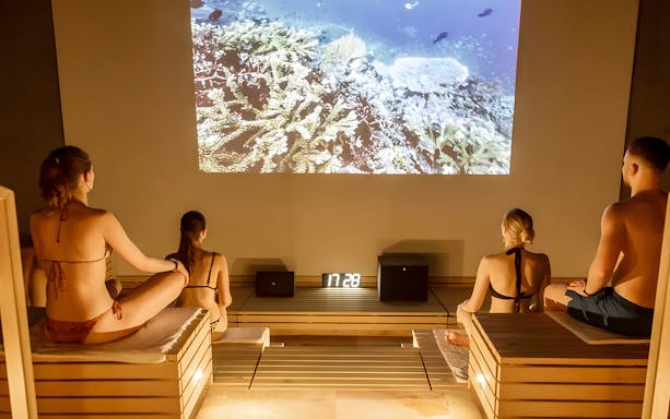 Visitors relaxing in a sauna at Therme Bucuresti Spa, watching an underwater video.
