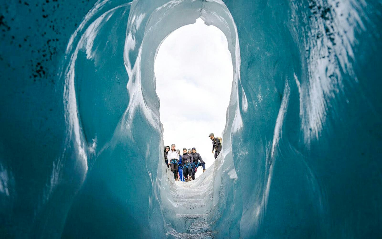 Guests hiking through an ice cave on Sólheimajökull glacier in Iceland.