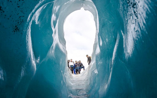 Guests hiking through an ice cave on Sólheimajökull glacier in Iceland.