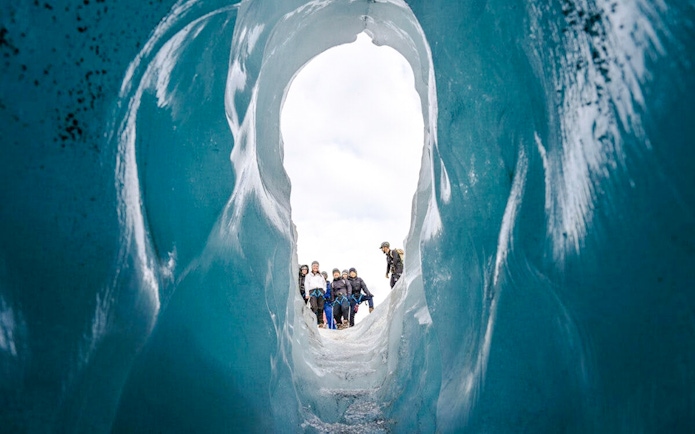 Guests hiking through an ice cave on Sólheimajökull glacier in Iceland.