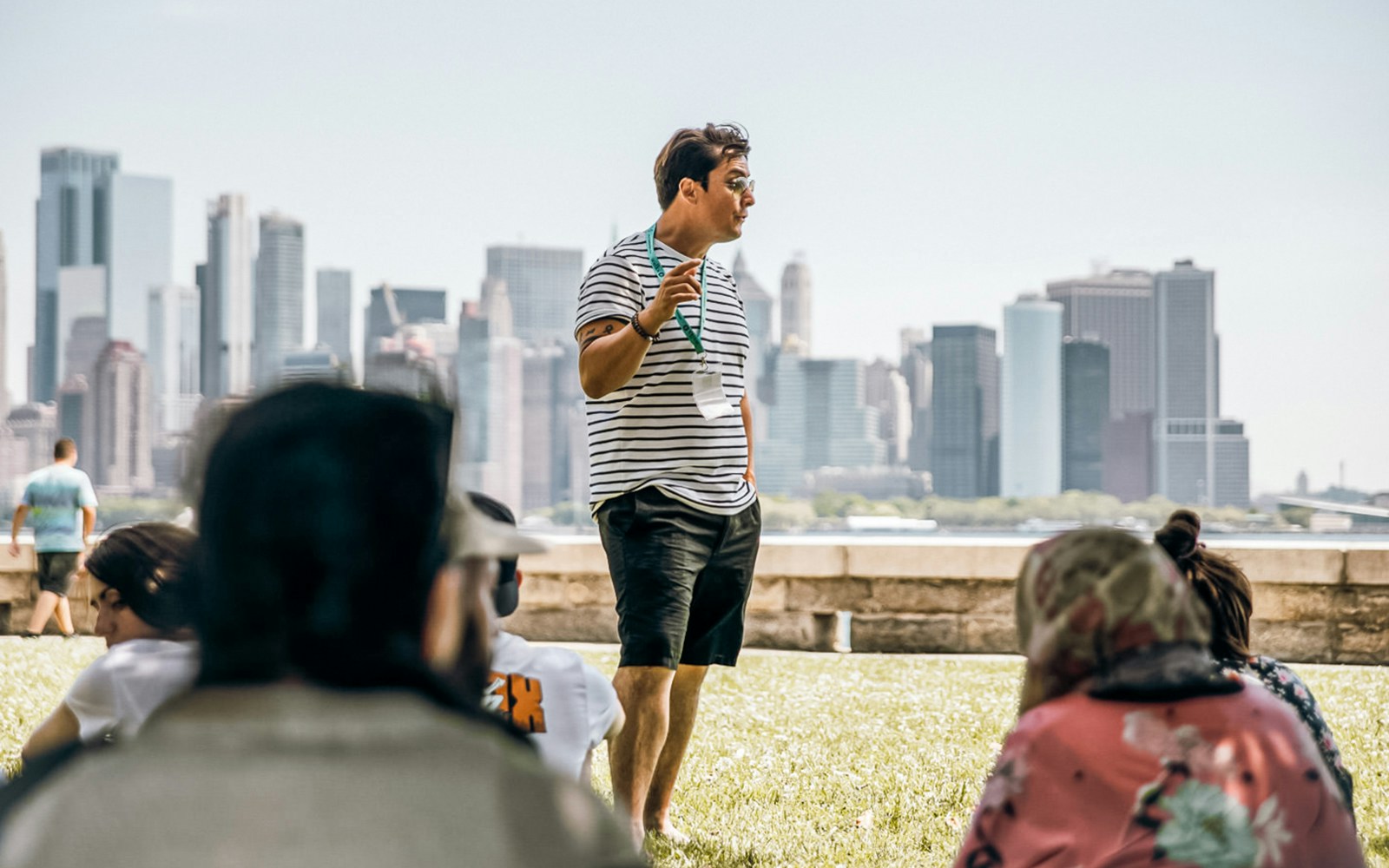 Tour guide speaking to a group with New York City skyline in the background.