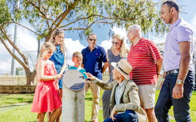 Tour group with guide at Sydney Cricket Ground, viewing a commemorative plaque.